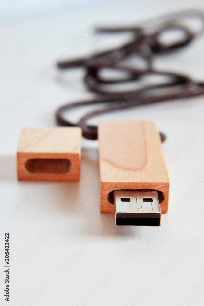Wooden surface flash drive for storing memory with blurred brown twine on light background at shallow depth of field with copy space for text. Wooden surface flash drive for storing memory with blurred brown twine on light background at shallow depth of field with copy space for text.
