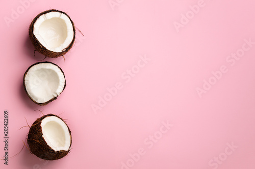 Pattern with ripe coconuts on pink background. Top View. Copy Space. Pop art design, creative summer concept. Half of coconut in minimal flat lay style.