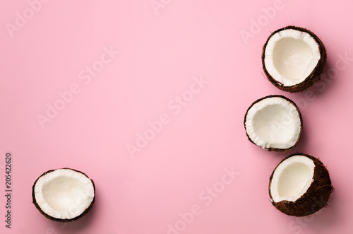 Wzór z dojrzałych kokosów na różowym tle. Widok z góry. Kopiuj przestrzeń. Projekt pop-artu, koncepcja kreatywnego lata. Połowa kokosa w minimalistycznym stylu płasko ułożonym.