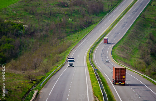 A hilly road with unseen horizon and driving lorries