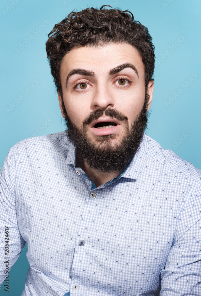 Obraz premium Portrait of a young man with a surprised face and open mouth. Stylish appearance, mustache and beard
