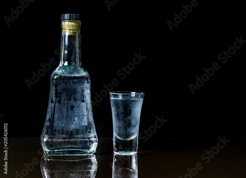Bottle of vodka and glass on dark background