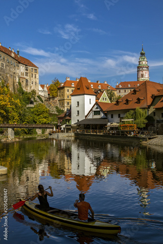 Cesky Krumlov, view on Vltava river and castle reflected in water . Boat with people rafting along the  river in the sunny day. Czech Republic.Historical city. European travel.