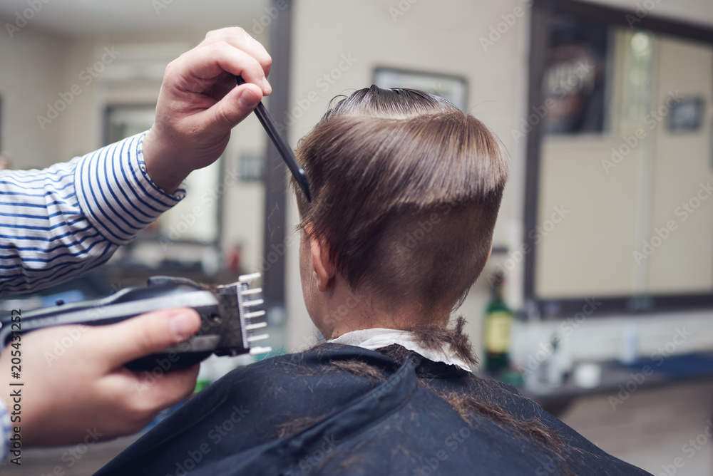 Barber is cutting a hair to Caucasian boy in barbershop. Barber is cutting a hair to Caucasian boy in barbershop.