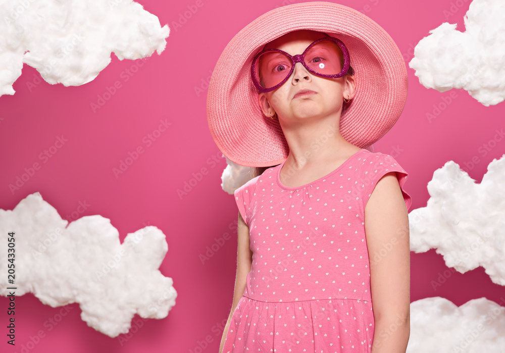 fashionable girl posing on a pink background with clouds, pink dress and hat fashionable girl posing on a pink background with clouds, pink dress and hat
