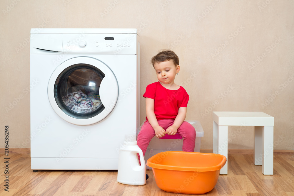 Little girl sitting near the washing machine Little girl sitting near the washing machine