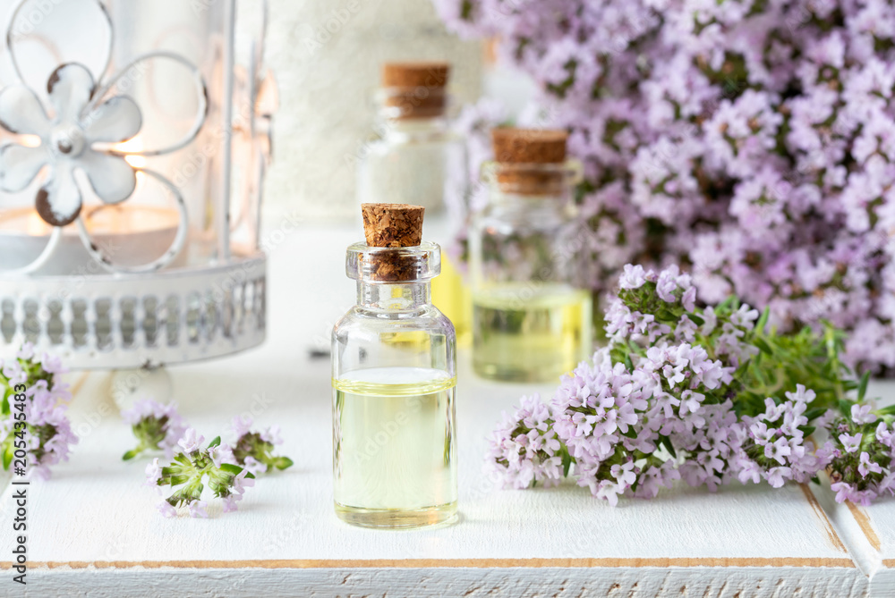 A bottle of essential oil with fresh blooming thyme A bottle of essential oil with fresh blooming thyme
