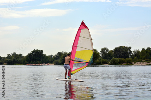 man stands on the Board in the water windsurfing
