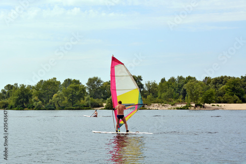 Windsurfing in the middle of the water in summer, people enjoy, sports and pleasure