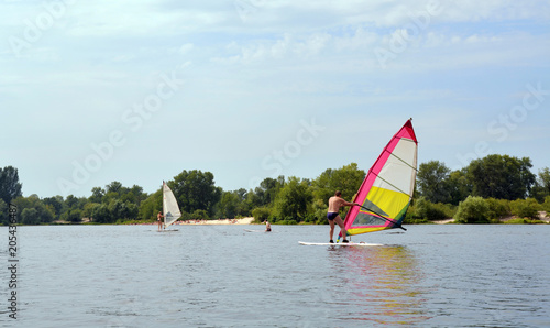 Windsurfing in the middle of the water in summer, people enjoy, sports and pleasure
