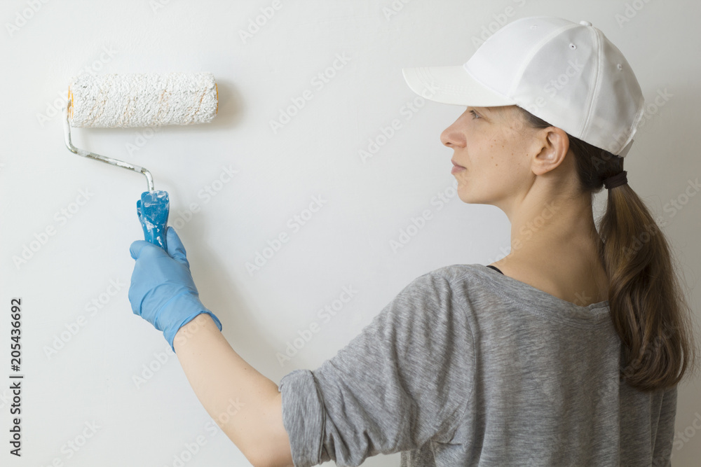 Fototapeta premium Girl painter paints a white wall.