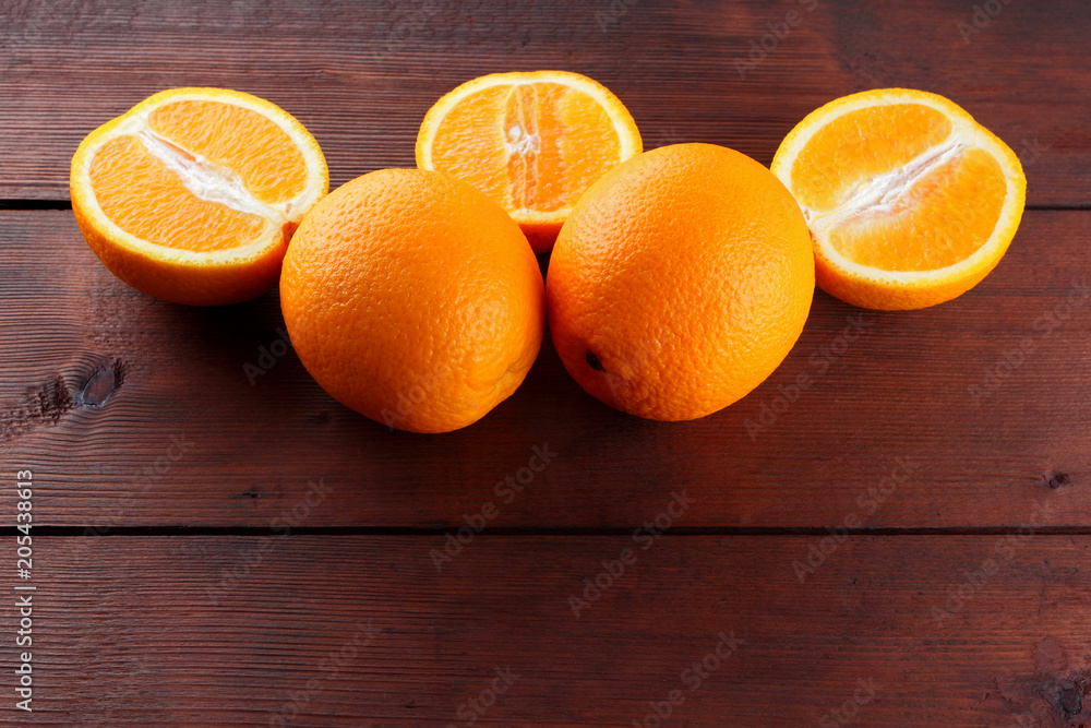 Fruits of oranges on a dark brown wooden background, halves of oranges on wooden boards. Copy space. Orange fruits for vegans. Citrus for breakfast Fruits of oranges on a dark brown wooden background, halves of oranges on wooden boards. Copy space. Orange fruits for vegans. Citrus for breakfast