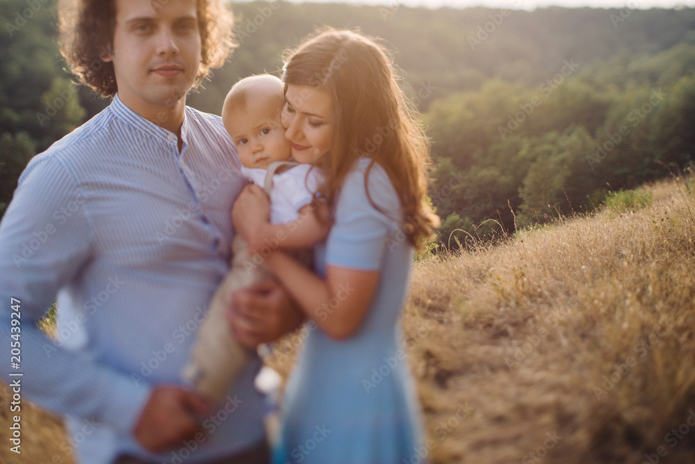 Young happy caucasian couple with baby boy. Parents and son having fun together. Mother and father play with toddler outdoors. Family, parenthood, childhood. Tilt-shift image, soft selective focus. Young happy caucasian couple with baby boy. Parents and son having fun together. Mother and father play with toddler outdoors. Family, parenthood, childhood. Tilt-shift image, soft selective focus.