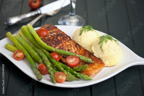 Baked salmon garnished with asparagus and tomatoes with herbs and mashed potatoes