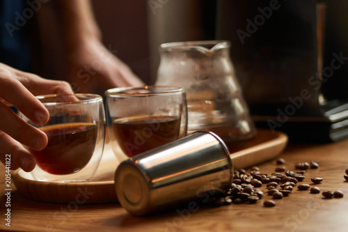 Professional Barista or coffee barman prepares coffee by an alternative method of brewing, pour over, by hot water spilling through a special filter with ground powder