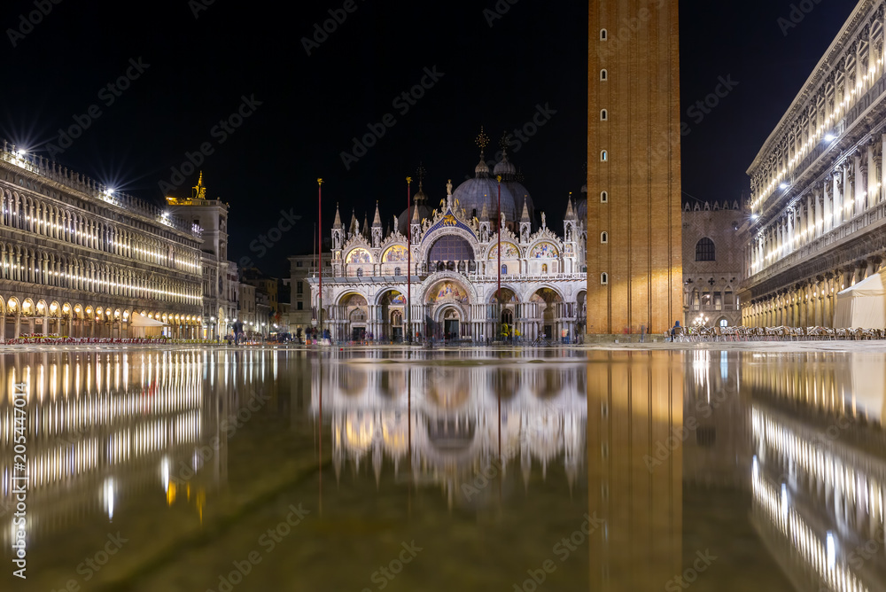 Fototapeta premium Bazylika na placu San Marco w Wenecji z odbiciem w nocy podczas przypływu lub aqua alta, która zalała plac wodą morską