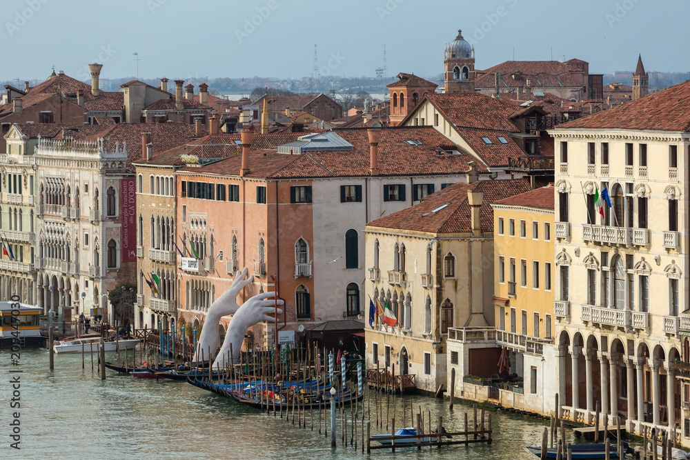 Obraz premium Olbrzymie ręce wznoszą się z wody Grand Canal, by wesprzeć budynek w Wenecji. Ten potężny raport na temat zmian klimatycznych autorstwa artysty Lorenzo Quinna. Zabytki Wenecji.