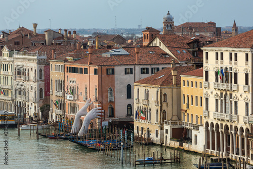 Giant hands rise from the water of Grand Canal to support the building in Venice. This powerful report on climate change from the artist Lorenzo Quinn. Venice landmarks.