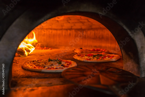 Original neapolitan pizza margherita in a traditional wood oven in Naples restaurant, Italy