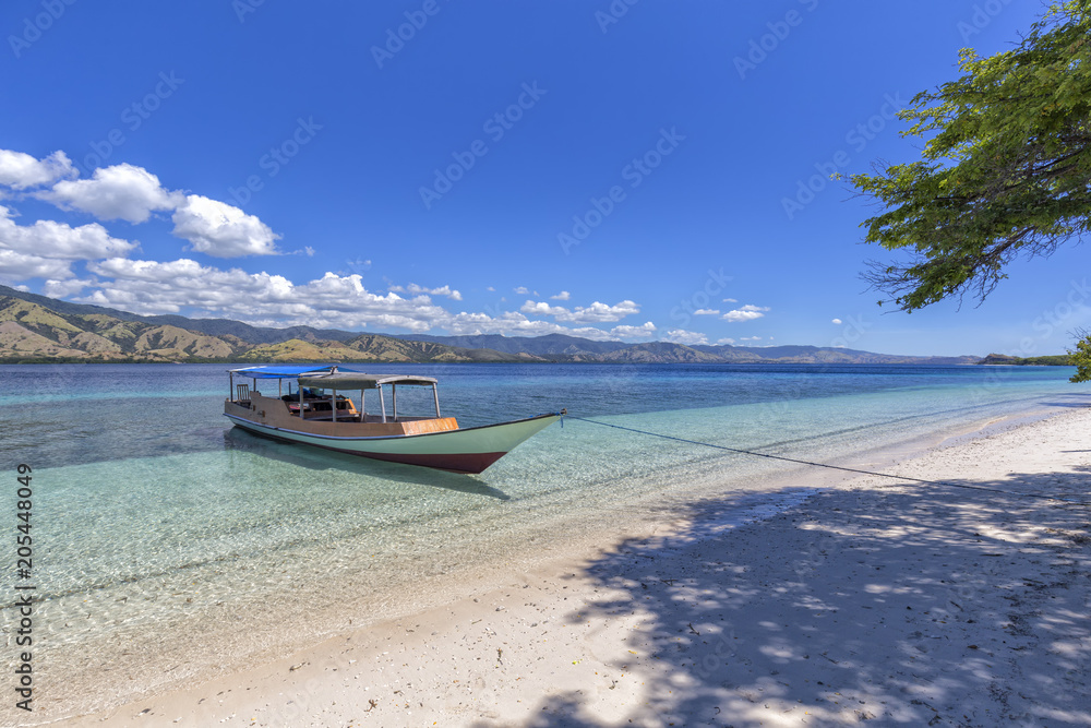 A boat docked on a beautiful empty tropical indonesian Beach in the Seventeen Island National Park. A boat docked on a beautiful empty tropical indonesian Beach in the Seventeen Island National Park.