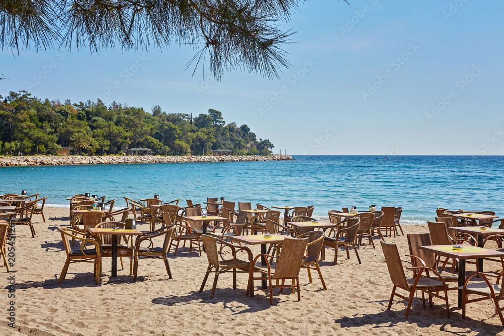 Tables and chairs on terrace in outdoor restaurant with view in Kemer, Turkey.