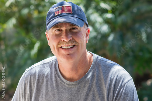 Smiling senior male wearing USA patriotic baseball hat in natural light