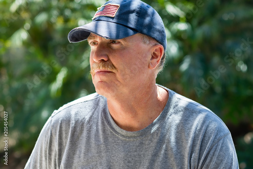 Adult male looking away wearing a baseball cap outside in natural light