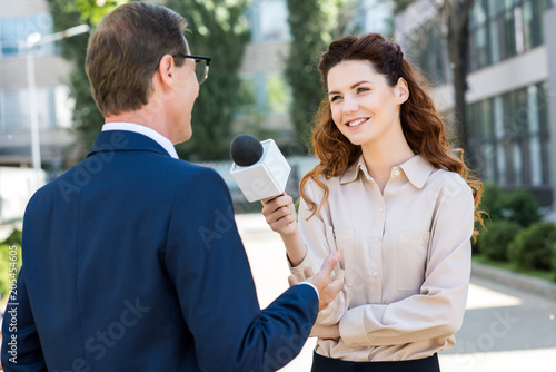Photos smiling female journalist taking interview with businessman