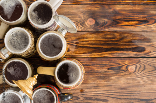 Frothy mugs of beer on timber bar with copy space