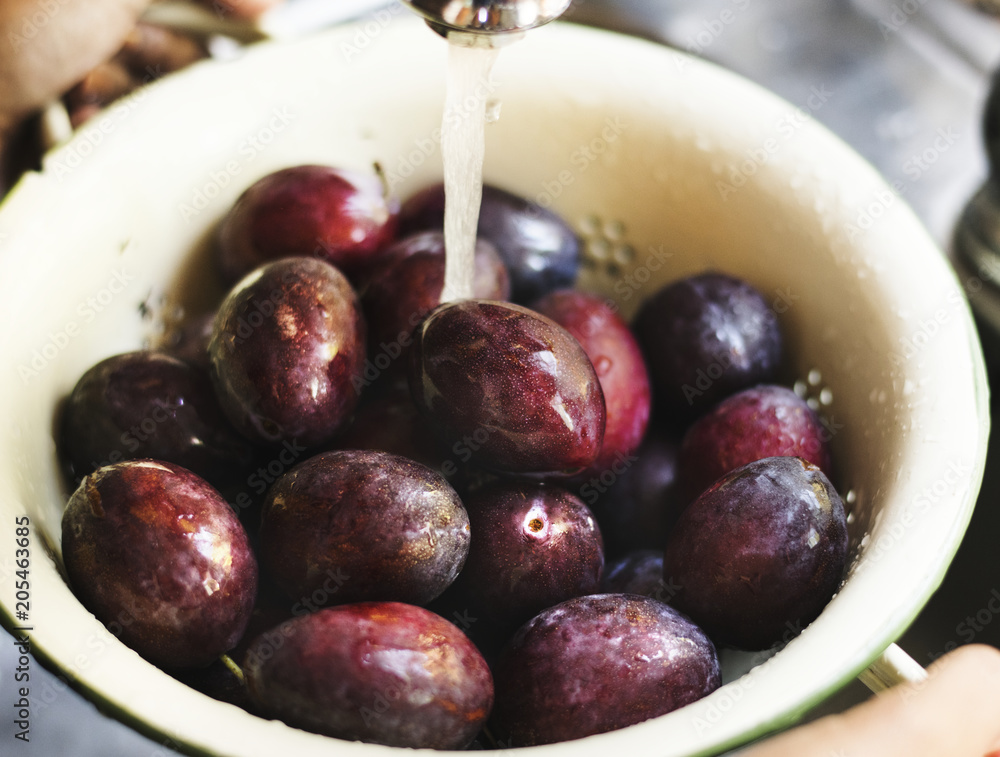 Organic plums being washed under running water food photography recipe idea Organic plums being washed under running water food photography recipe idea