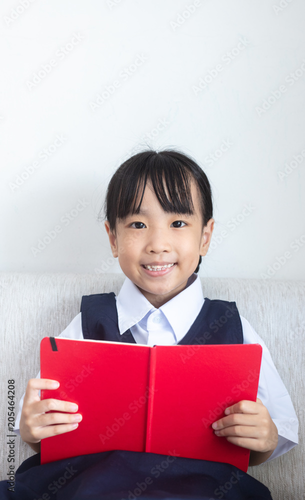 Asian Chinese little girl sitting on the sofa reading book