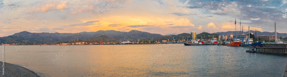 Black Sea coastline, seaport and bay with boats. Beautiful evening sky. Panoramic view of Batumi city in Georgia. Tourism center.