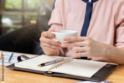 Business and finance concept, Businesswoman holding coffee cup and discussing sale analysis Chart in coffee shop