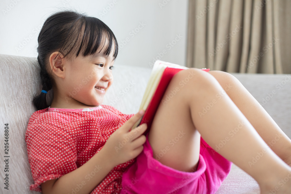 Asian Chinese little girl sitting on the sofa reading book Asian Chinese little girl sitting on the sofa reading book