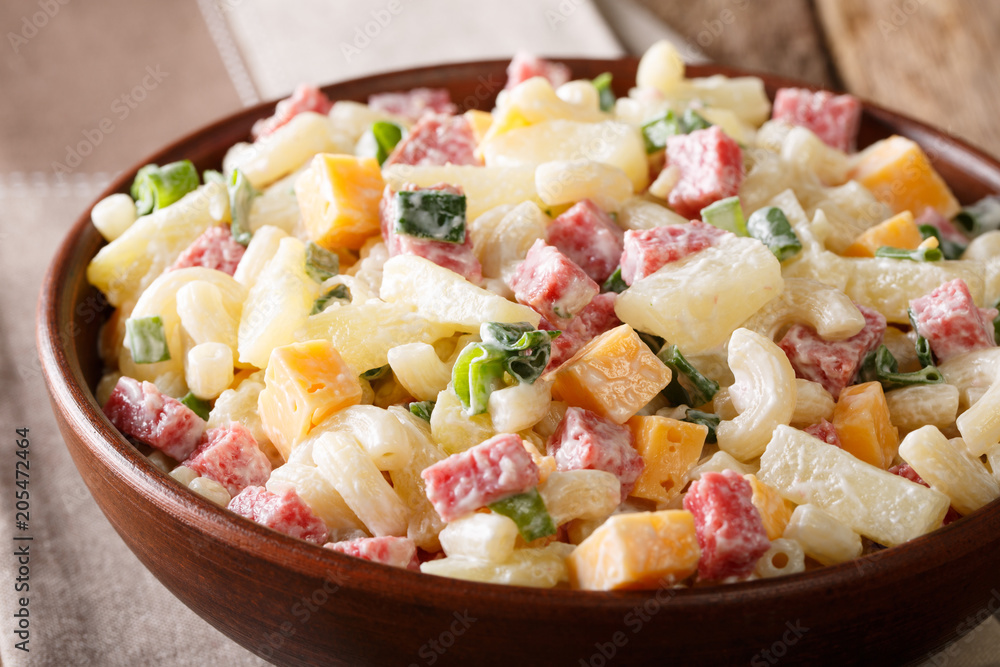 hearty Hawaiian salad with pasta, ham, pineapple, onion, cheddar cheese dressed with mayonnaise close-up. horizontal
