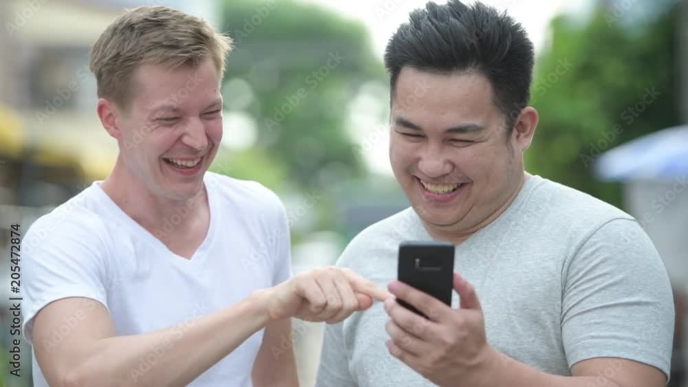Two young multi-ethnic handsome men together in the streets outdoors