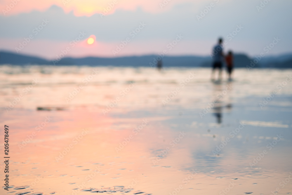 Blurred background of people enjoying life on summer beach in sunset.