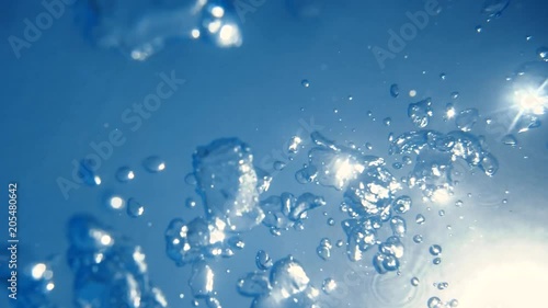 Air bubbles rising up to surface in blue pure ocean. Sunshine penetrating crystal clear sea water. Person drowning.