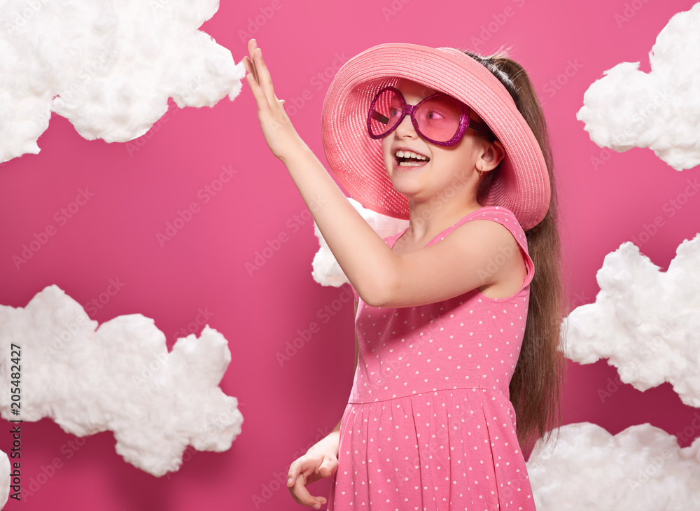 fashionable girl posing on a pink background with clouds, pink dress and hat fashionable girl posing on a pink background with clouds, pink dress and hat
