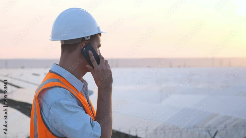 technical expert in solar energy photovoltaic panels, remote control performs routine actions for system monitoring using clean, renewable energy. concept of remote support technology. make phone call technical expert in solar energy photovoltaic panels, remote control performs routine actions for system monitoring using clean, renewable energy. concept of remote support technology. make phone call