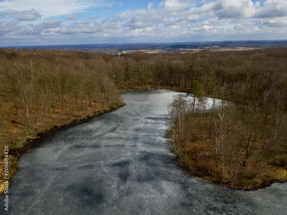 Aerial view during winter over frozen lake in forest of Söderåsen National Park , located in Skåne county in Sweden