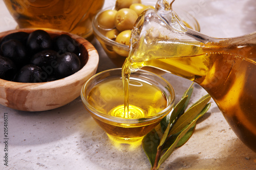 Bottle virgin olive oil and oil in a bowl with some olives