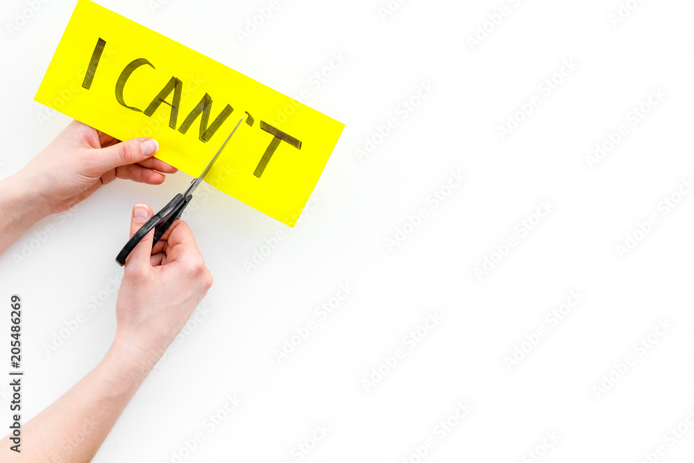 I can concept. Motivate youself, believe in yourself. Hand cut off the letter t of written word I can't by sciccors. White background top view copy space I can concept. Motivate youself, believe in yourself. Hand cut off the letter t of written word I can't by sciccors. White background top view copy space