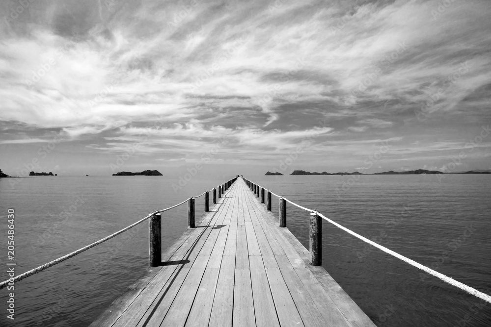 Fototapeta premium Czarno-biały Krajobraz drewniany most w błękitne morze na tropikalnej plaży.