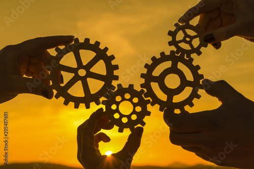team of people with gears in hands on sunset background. business. interaction.