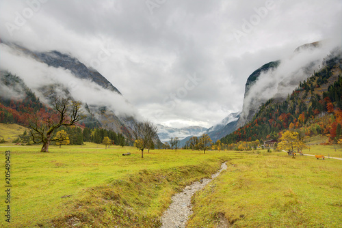 A hiking path through the meadow with maple trees on the mountainside under cloudy moody sky ~ Beautiful autumn scenery of Karwendel Mountains in Eng, Hinterriss, Austria ~ European alps © AaronPlayStation