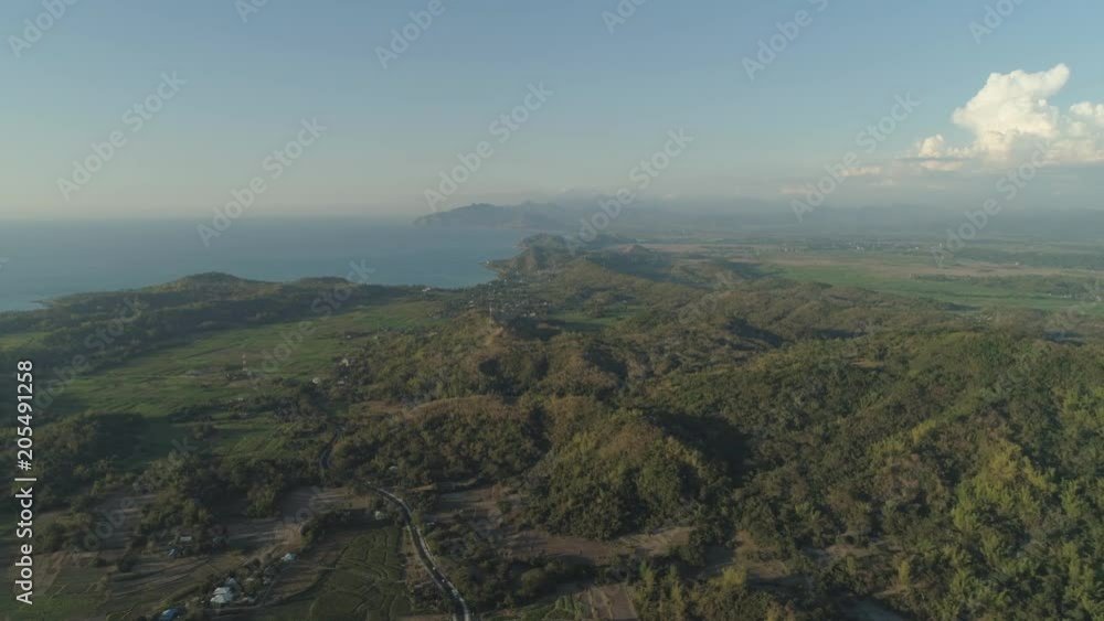 Aerial view of sea shore and mountains covered with green forest, trees with sky and clouds. Philippines, Luzon. Tropical landscape in Asia. Aerial view of sea shore and mountains covered with green forest, trees with sky and clouds. Philippines, Luzon. Tropical landscape in Asia.