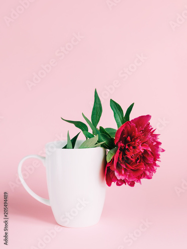 A white cup with pink flower inside. Trendy vertical background with peony.