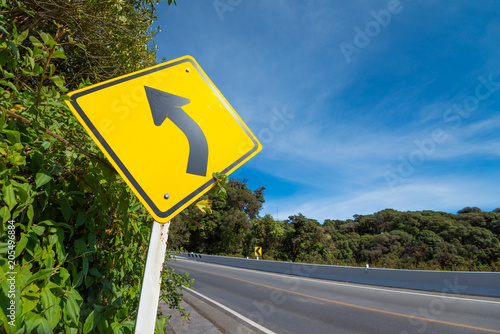 Yellow traffic signs say the curve left direction on mountain highway, warning accident