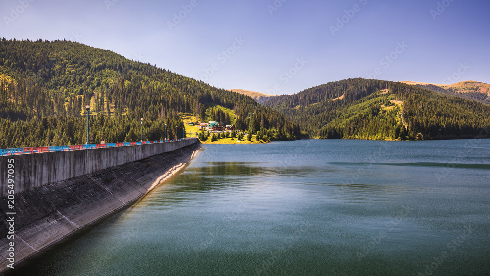 View to Bolboci lake from the damb with carpathian mountains at the background, Sinaia, Romania.